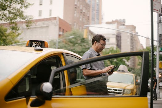 Calm man in glasses standing near taxi and looking at smartphone on street in city in daytime